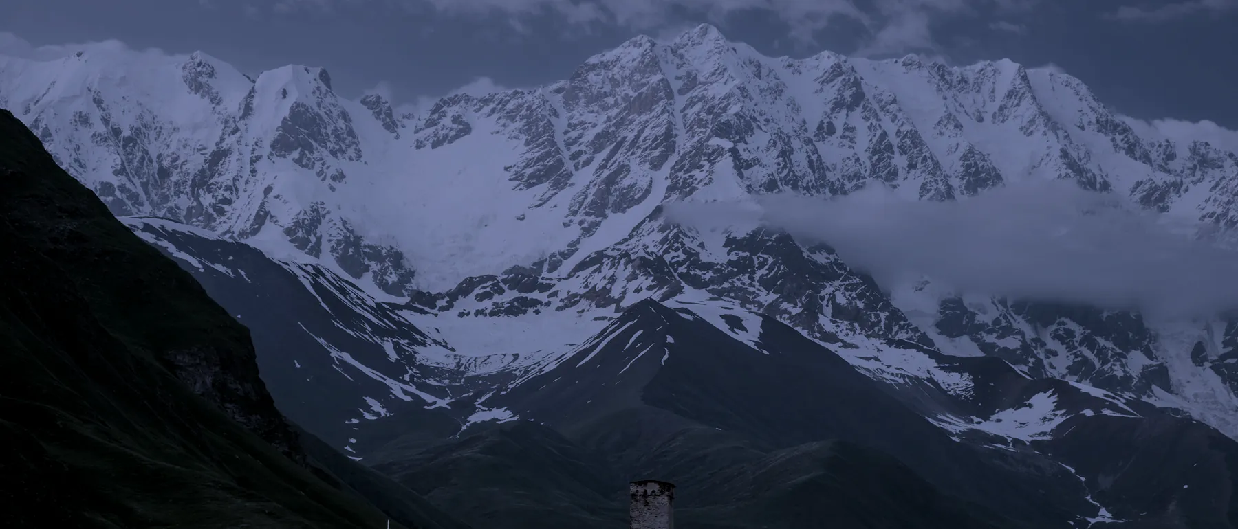 The Greater Caucasus range above Svaneti at nightfall, with a Svan tower in the foreground